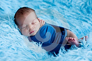 Cute baby boy, peacefully sleeping wrapped in blue wrap