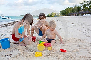 Cute baby boy playing with beach toys on tropical beach