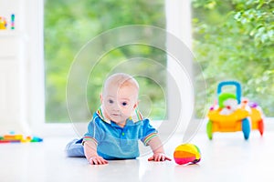 Cute baby boy playing with colorful ball and toy car