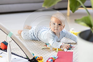 Cute baby boy playing with hanging toys arch on mat at home Baby activity and play center for early infant development