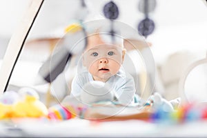 Cute baby boy playing with hanging toys arch on mat at home Baby activity and play center for early infant development