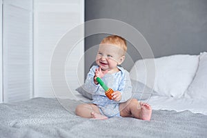 Cute baby boy playing with knitted toy on bed at home