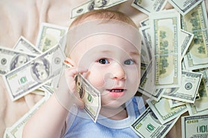 Cute baby boy playing with a lot of money like talking on telephone, american hundred dollars cash