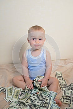 Cute baby boy playing with money, hundreeds of dollars