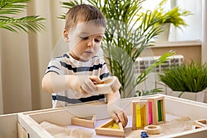 Cute baby boy playing sand table therapy toys developing game at home. Early development