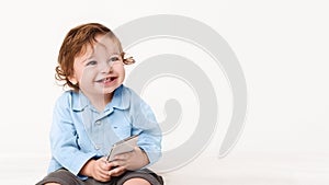 Cute baby boy playing with smartphone, copy space