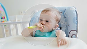 Cute baby boy playing with spoon while eating porridge