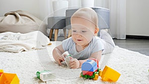 Cute baby boy playing with toys on soft carpet at home. Child education and development