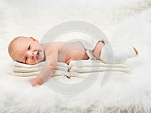 Cute baby boy relaxing on stack of towels