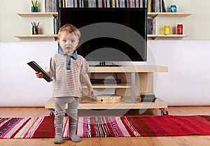 Cute baby boy with remote control in front of the TV