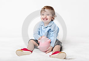 Cute baby boy sitting on floor with piggy bank