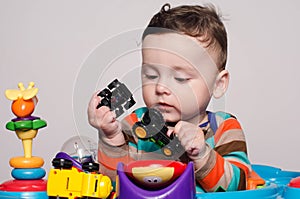Cute baby boy sitting and playing with toys.