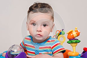 Cute baby boy sitting and playing with toys.