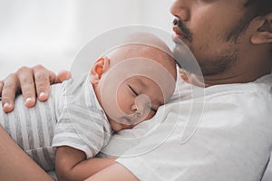 Cute baby boy sleeping on father`s chest