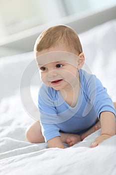 Cute baby boy smiling and sitting on the bed