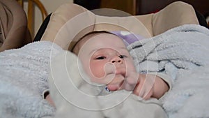 Cute baby boy stretching his legs in baby bouncer and starting to cry