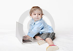Cute baby boy typing on laptop keyboard