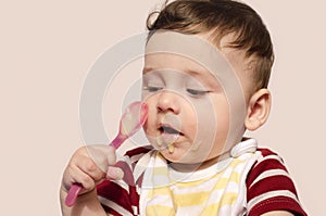 Cute baby boy wanting to eat baby food with the spoon.