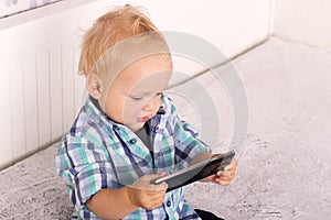 Cute baby boy watching cartoons in smartphone. Funny toddler playing with phone