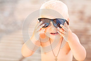 Cute baby boy wearing sunglasses on the beach