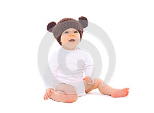 Cute baby in brown knitted hat sitting on white