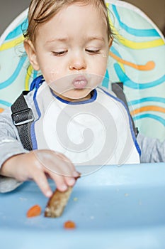 Cute baby child eating by itself and not liking the food