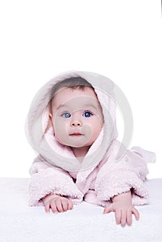 Cute baby child in pink bathrobe lying down on blanket