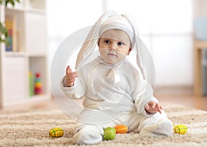 Cute baby child in rabbit costume sittng on froor in nursery