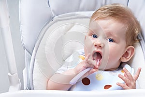 Cute baby in a child seat eats porridge. First lure Close up