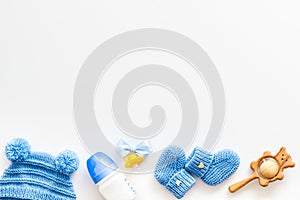 Cute baby clothes for boy, rattle, bottle and dummy on white background top view copyspace