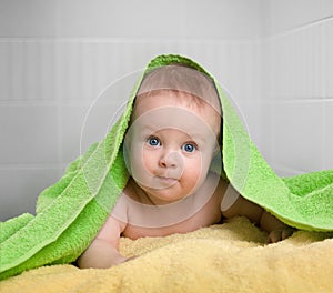 Cute baby in colorful bathing towel in bathroom