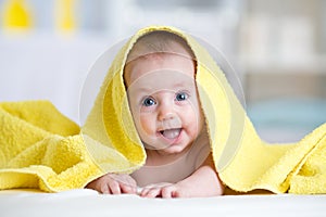 Cute baby covered with a bath towel lying on tummy in the bathroom