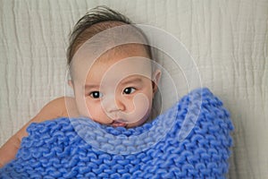 Cute baby covered in blue towel quilt making various expressions