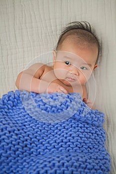 Cute baby covered in blue towel quilt making various expressions