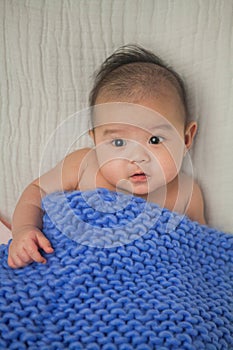 Cute baby covered in blue towel quilt making various expressions