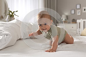 Cute baby crawling on bed at home