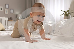 Cute baby crawling on bed at home