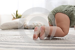 Cute baby crawling on floor at home, closeup