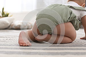 Cute baby crawling on floor at home, closeup