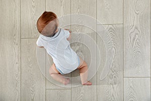 Cute baby crawling on floor, top view