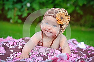 Cute baby crawling outdoors in brown knitted cap