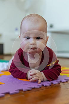 Cute baby crawling on the rug looking to the camera