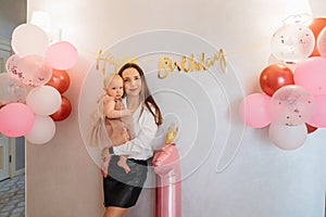 Cute baby daughter in an elegant dress with her mother. home party