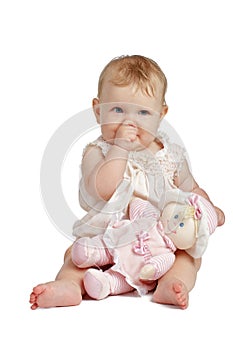 Cute baby with doll sucking thumb in sleeveless sundress