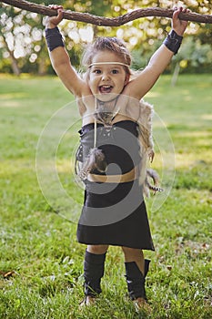 Cute baby dressed in the clothes of primitive people with combat staff