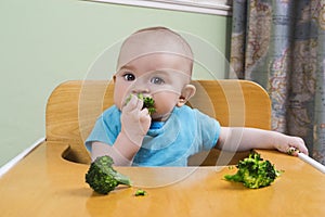 Cute baby eating broccoli