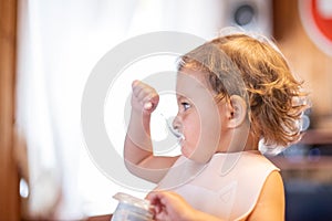 cute baby eating yogurt with spoon by himself. adorable toddler has lunch. hungry child.