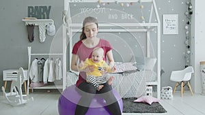 Cute baby enjoying mom`s fitness workout on Ball