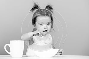 Cute baby food, babies eating. Happy infant baby girl with spoon eats itself.