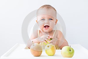 cute baby girl in baby chair eating apples. Baby first solid food